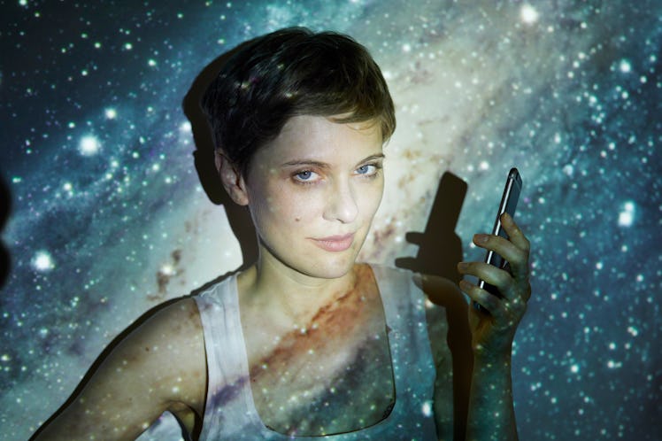 A woman holding her phone and doing the planet wallpaper trend.