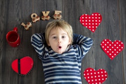 Cute toddler blond child, cute boy with valentine decoration, love, flowers, cake in studio