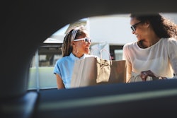 Two queer women load shopping bags into a car. Here's how to tell if someone likes you, according to...