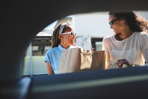 Two queer women load shopping bags into a car. Here's how to tell if someone likes you, according to...