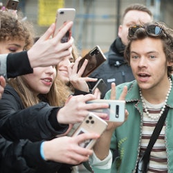 An overwhelmed Harry Styles takes a selfie with excited fans, or stans. What does Stan mean? Here's ...