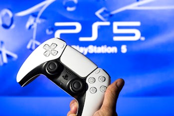 SPAIN - 2021/11/08: In this photo illustration, a PlayStation 5 controller seen with a PlayStation 5...