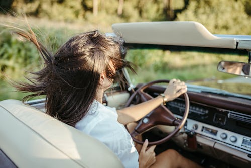 Woman with brown hair and sunglasses driving a retro convertible car. Keep seeing double numbers? He...