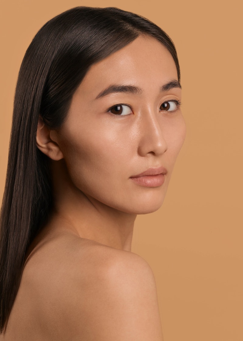 Asian brunette with flawless skin because of the best The Ordinary products for acne.