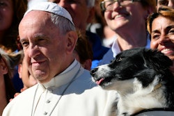 Pope Francis poses for a picture next to a dog after his general audience in St Peter's square at th...