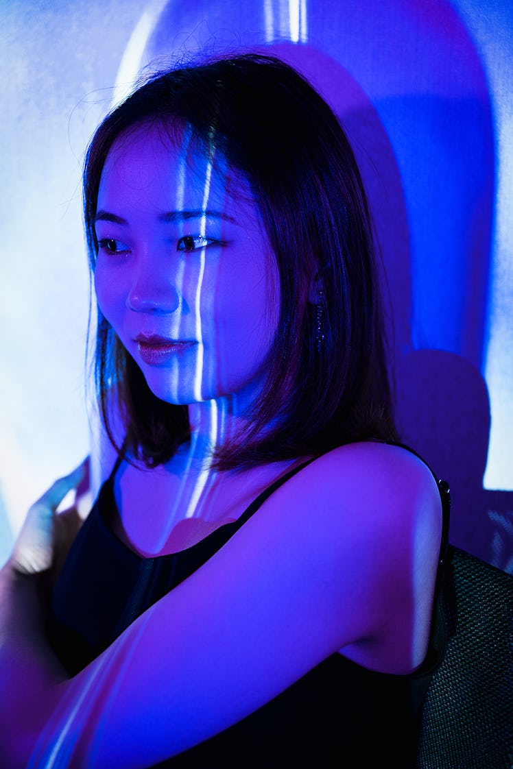 Young woman standing in violet neon light, thinking about the January 10, 2022 weekly horoscope for ...