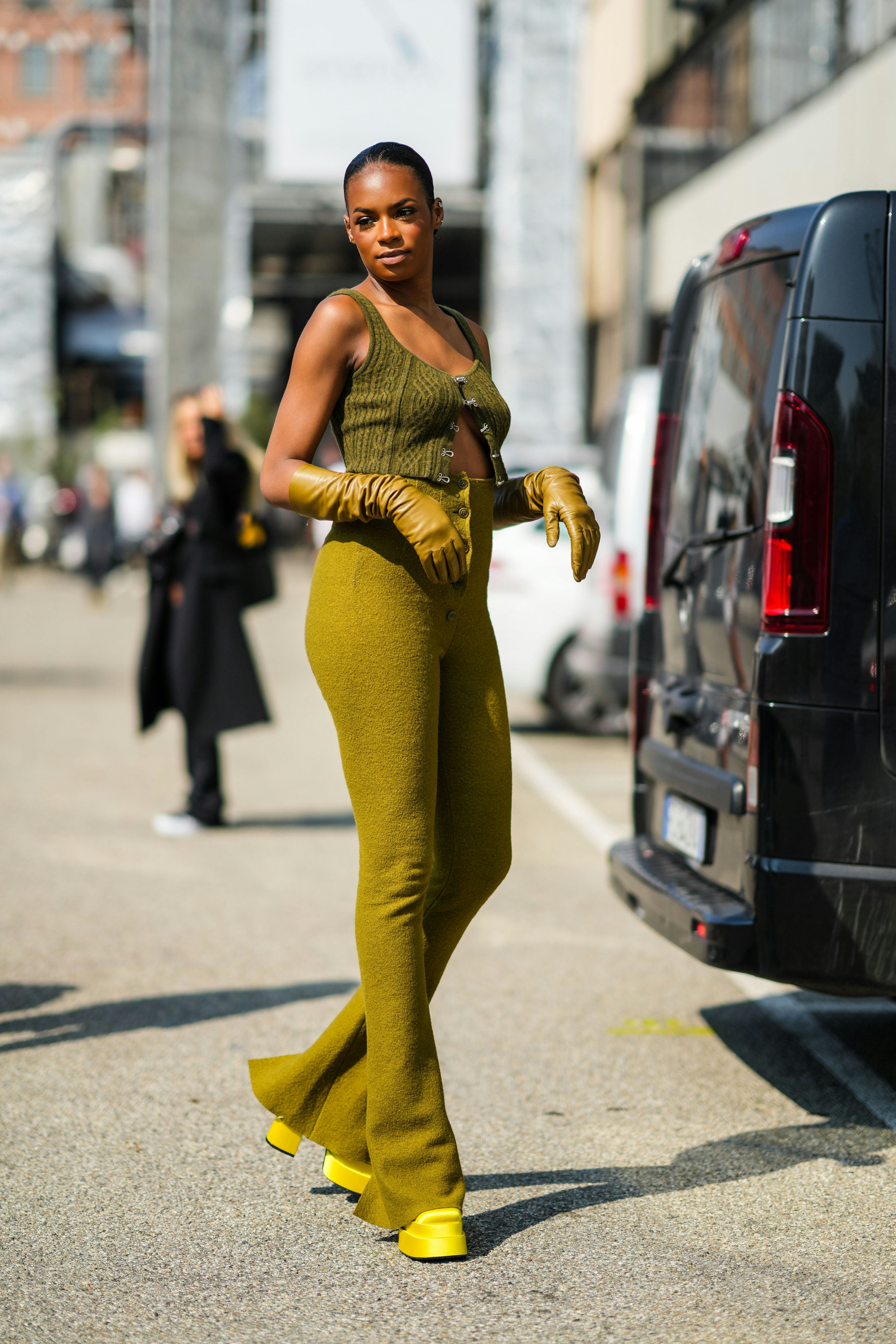 MILAN, ITALY - SEPTEMBER 24: A guest wears silver earrings, a khaki embossed pattern wool V-neck / s...
