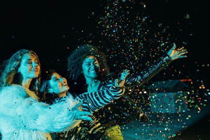 Three young women who are also best friends, throwing confetti in the air and celebrating the Januar...