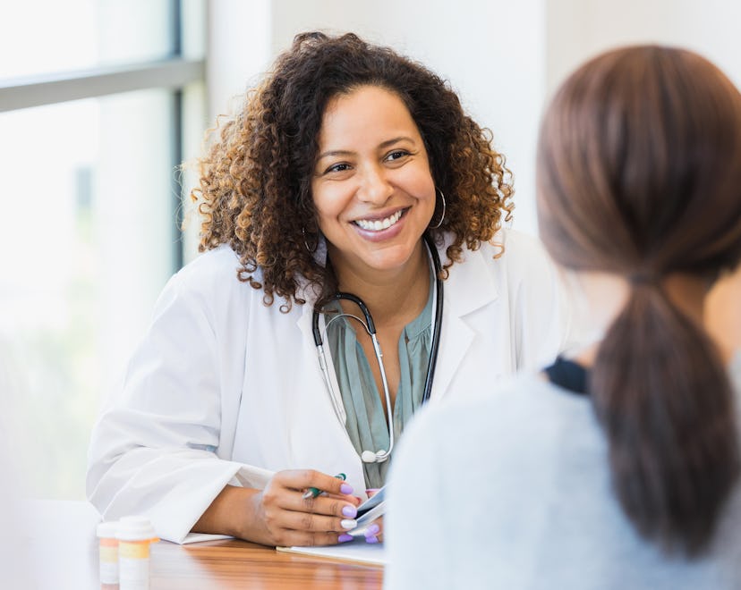 A smiling mid adult female doctor listens as a female patient discusses her health in an article abo...