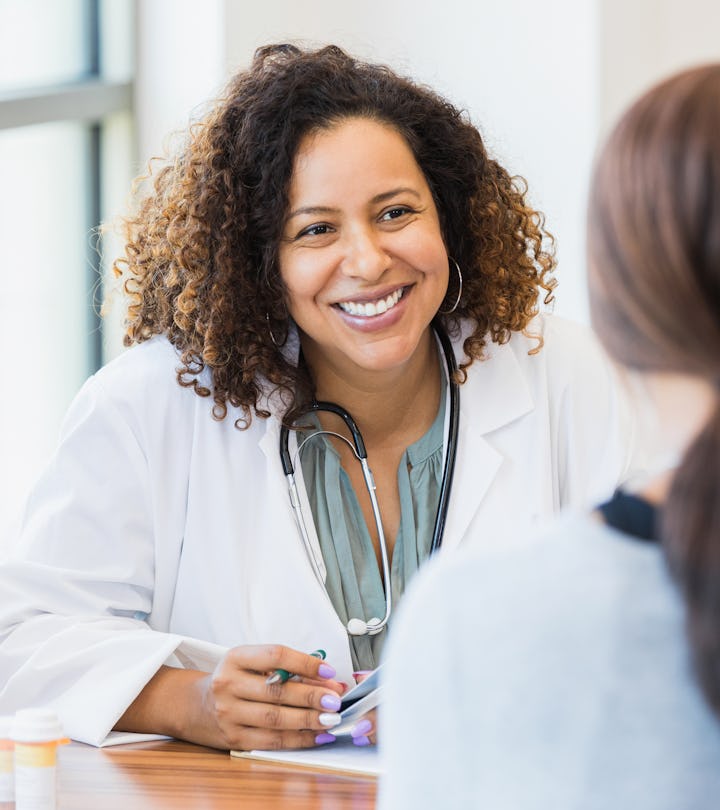 A smiling mid adult female doctor listens as a female patient discusses her health in an article abo...