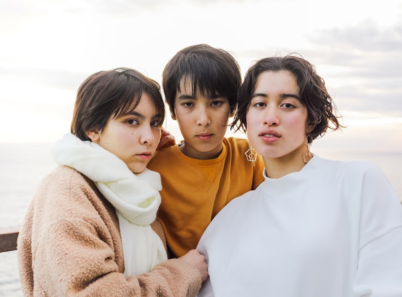 Three friends pose for a photo with serious expressions on their faces as they think about how the O...