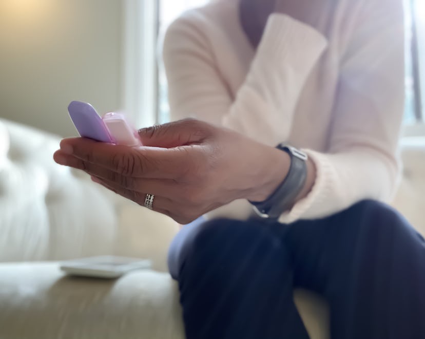 A hand holding two pregnancy tests in a story about how long does a miscarriage last.