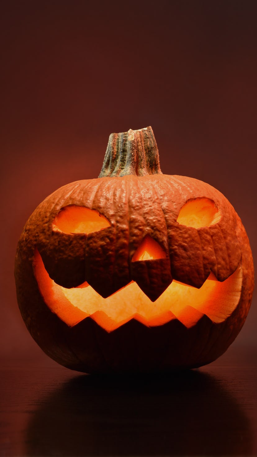 A carved jack-o'-lantern with spooky eyes and a candle inside, a classic jack-o'-lantern idea for 20...