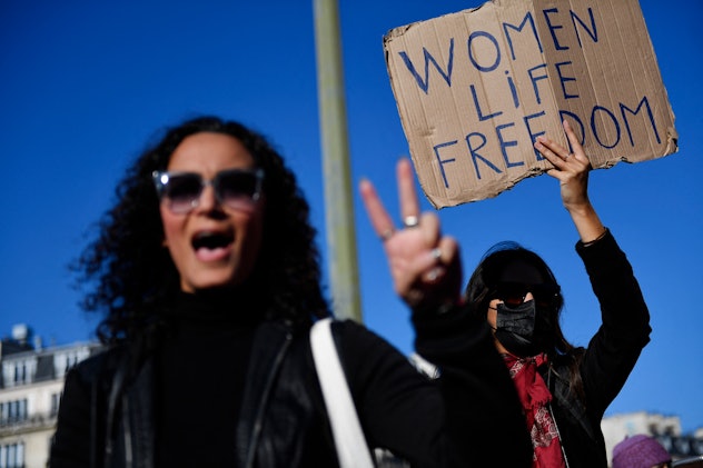 A demonstrator holds a placard (R) during a rally in support of Iranian protests, in Paris on Octobe...