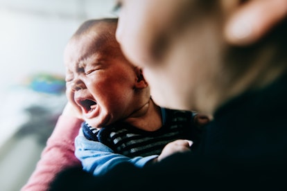 mother holding baby girl who is crying and irritable, a symptom of RSV