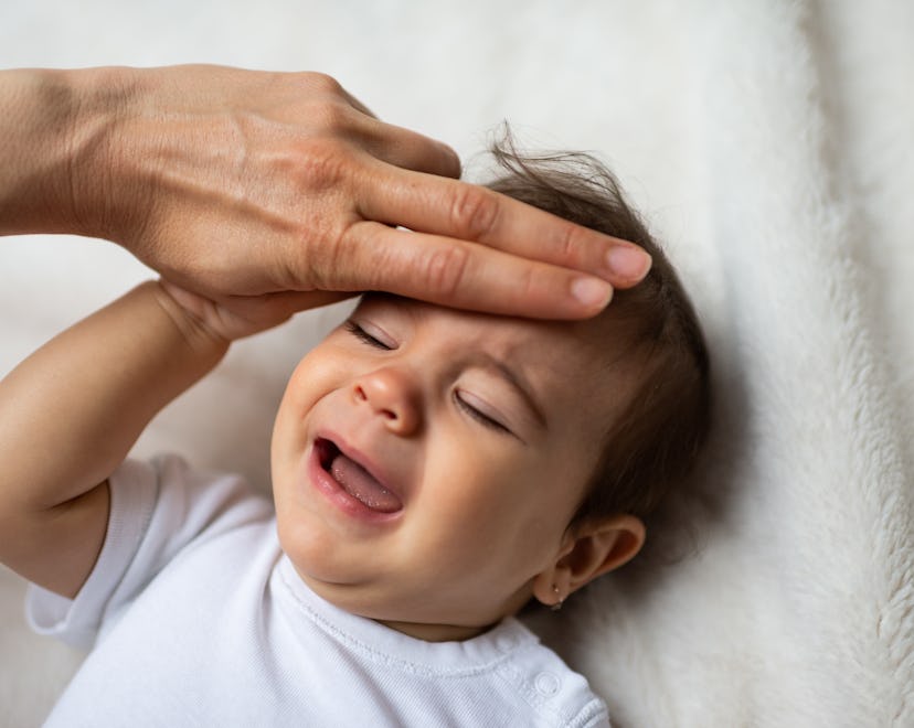 Young mother checking baby's temperature in the bedroom, guide to rsv in babies