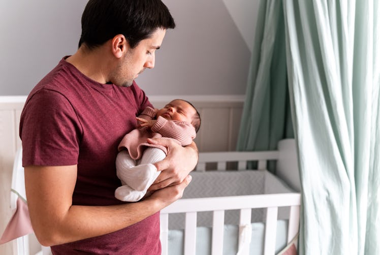 Father looking proudly at his newborn baby girl as he carefully holds her in his arms.