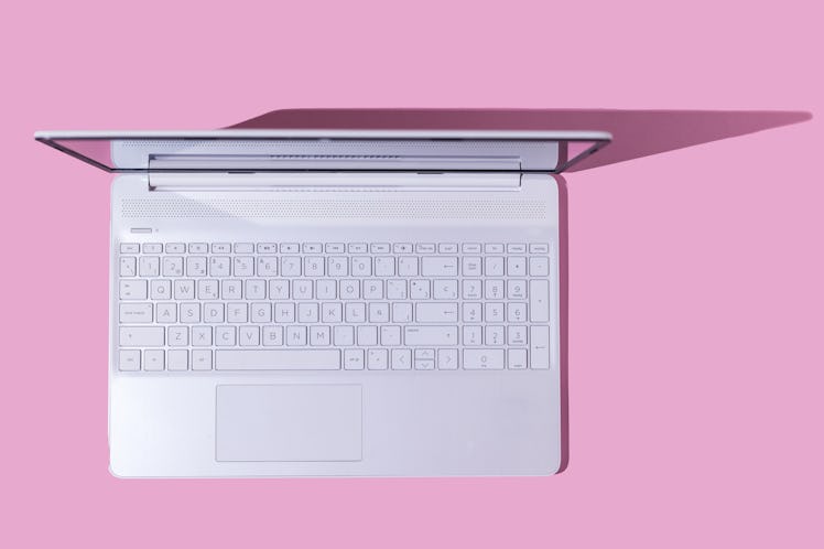 White laptop with hard shadow on pink background. Computer, Internet, PC, laptop and telecommuting c...