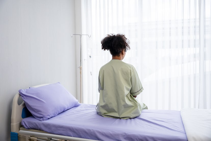 Lonely patient sitting on the hospital bed, facing a window, in an article about what I Am 1 in 4 me...