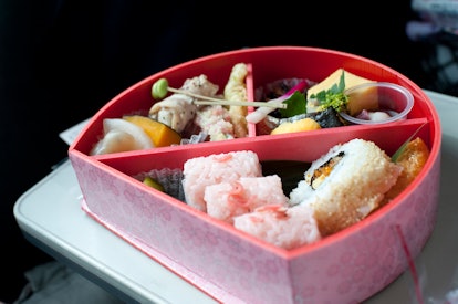 Serving of food inside a bento box, a lacquered container with internal divisions to house a complet...