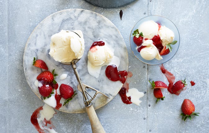 Vanilla ice cream served with fresh strawberries and chocolate, ice cream scoop and spoons, on ligh...