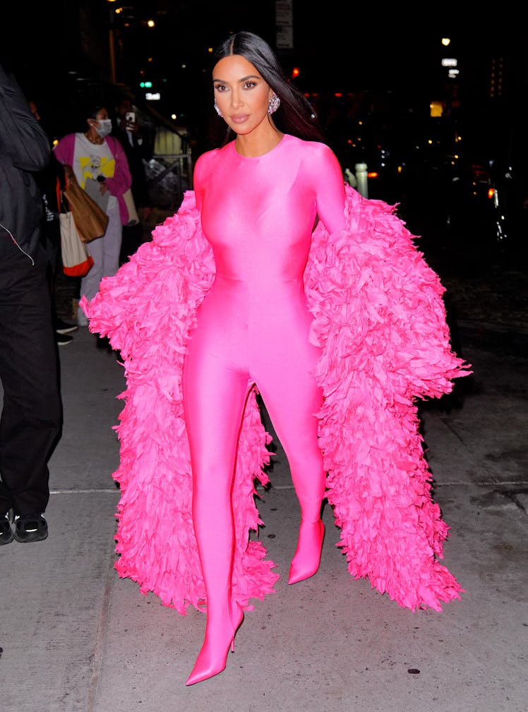 Kim Kardashian wearing a hot pink catsuit and feather coat as part of Kim Kardashian's style evoluti...