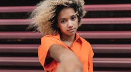 young woman reaches for camera with a serious expressing as she thinks about the spiritual meaning o...