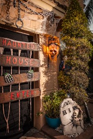 A house with a variety of haunted house decorations, including boarded up door, chains, a skull and ...