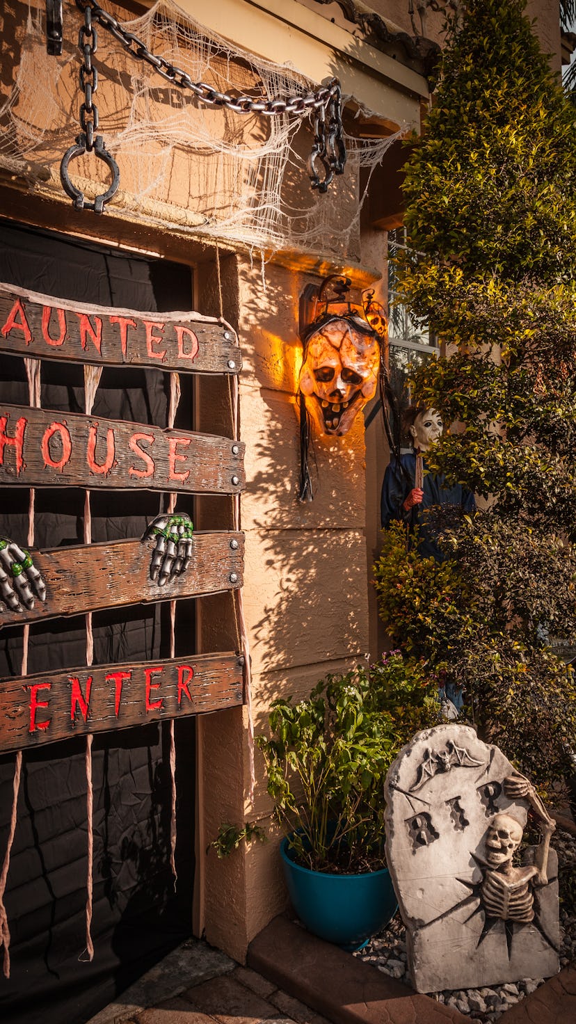 A house with a variety of haunted house decorations, including boarded up door, chains, a skull and ...