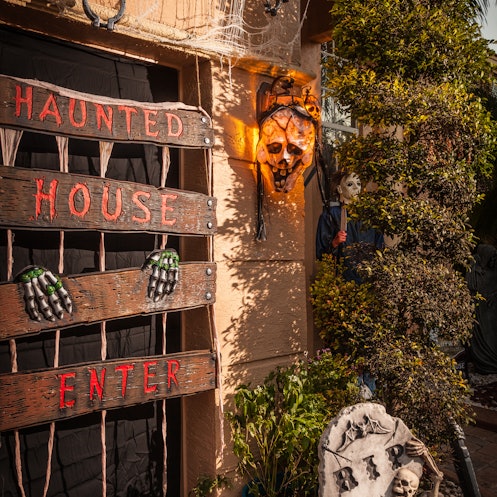 A house with a variety of haunted house decorations, including boarded up door, chains, a skull and ...