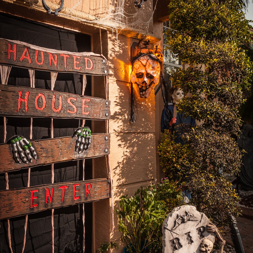 A house with a variety of haunted house decorations, including boarded up door, chains, a skull and ...