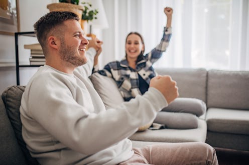 Happy couple cheering and watching sport game on TV