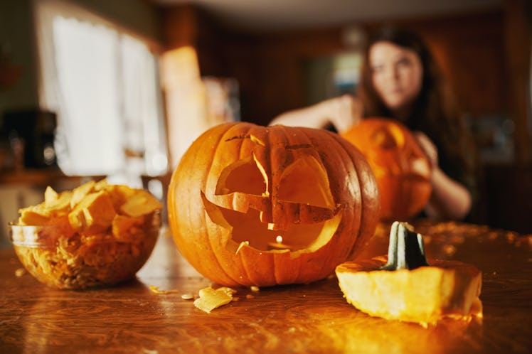 A woman carves three pumpkins as one of the luckiest zodiac signs on Halloween 2022.