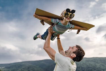 Happy father holding his son high-up while he is pretending to be an airplane.