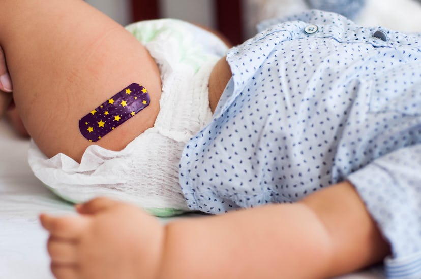 Close-up view of bandage over injection shot on baby's leg