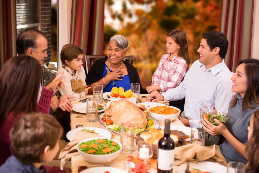 A family enjoying Thanksgiving dinner together around the dining table at grandmother's home. Thanks...