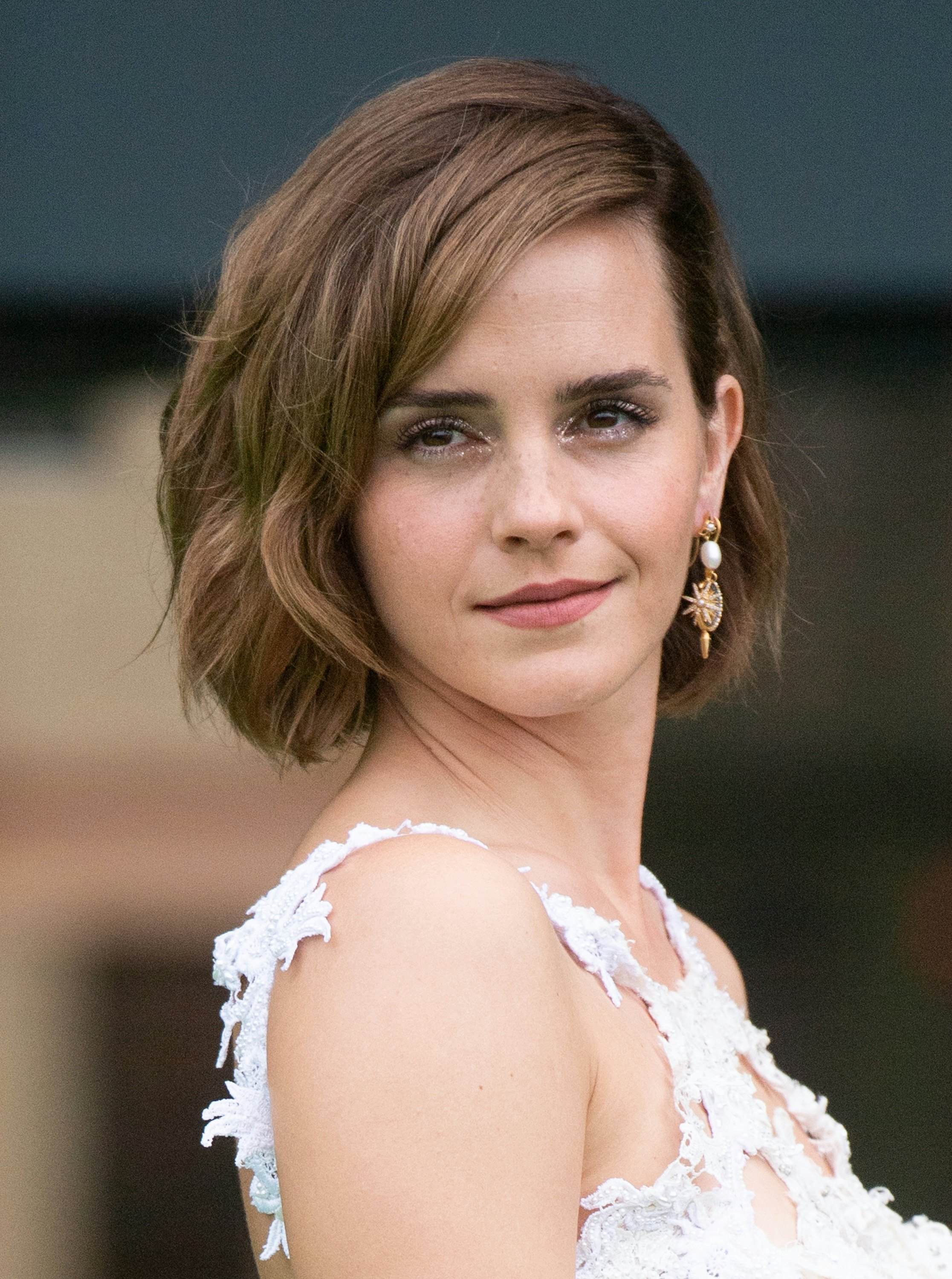 Emma Watson with her hair cut boyish short and around her ears in a pixie