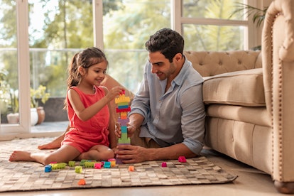 Girl making building blocks with her father at home
