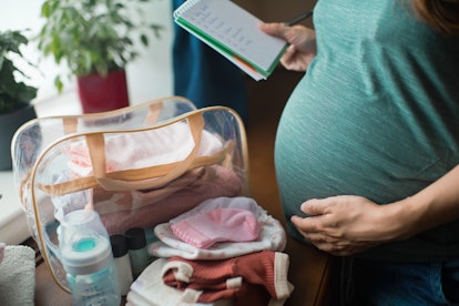 Pregnant woman at home preparing bag for newborn baby. in an article about soft cervix and what that...