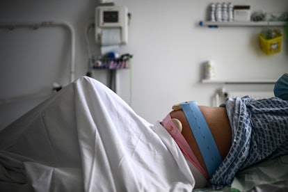 A pregnant woman lies on her bed with monitoring devices in an article about amniotic fluid and what...
