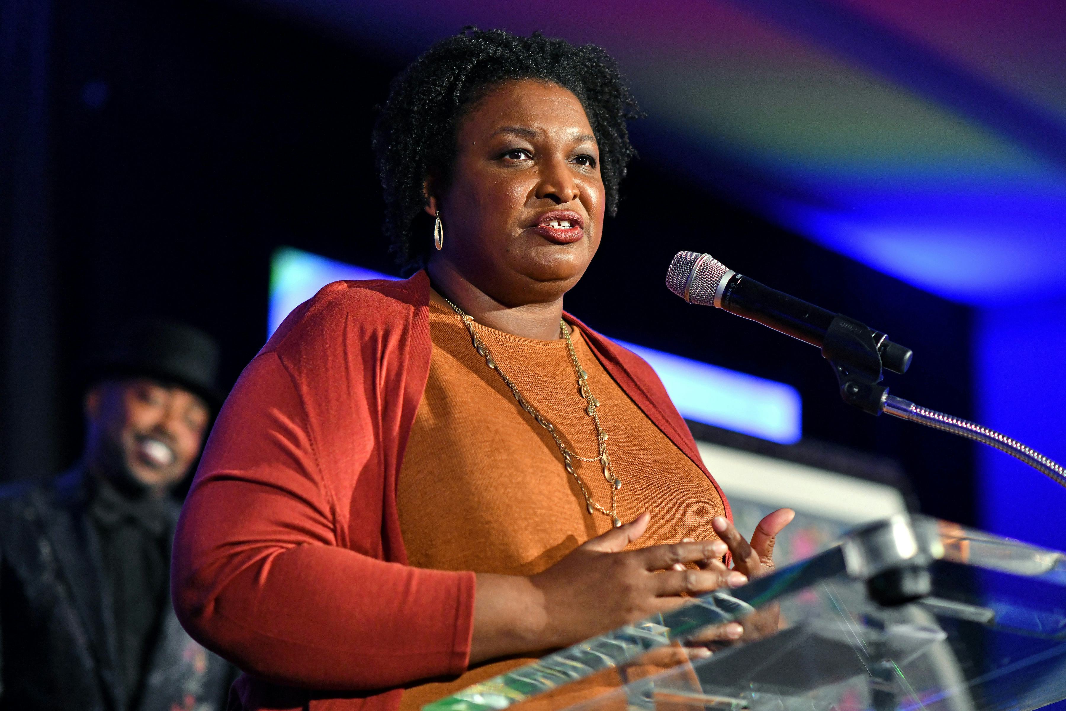 Stacey Abrams during her speech in an orange shirt and sweater combination