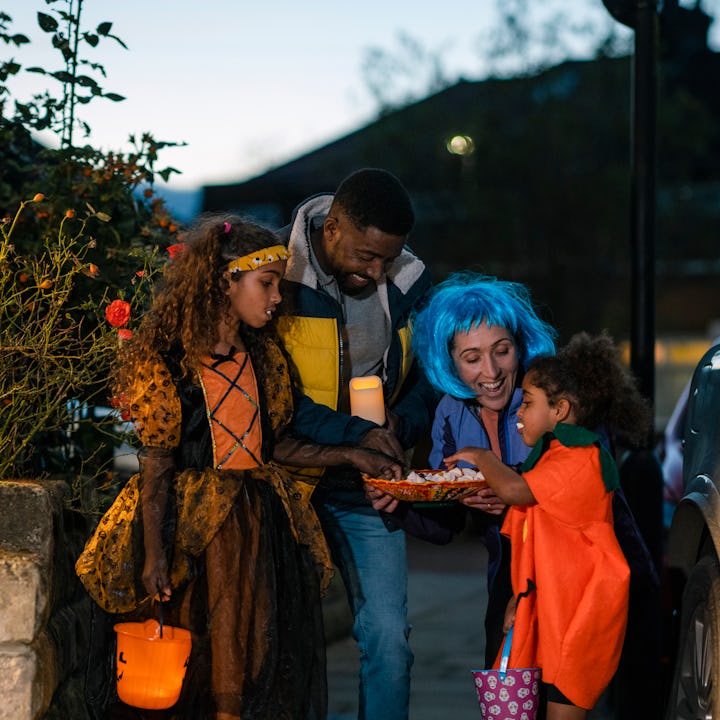 A family wearing fancy dress, out trick or treating in North East England during halloween. They are...