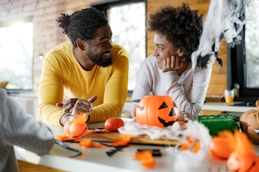 Happy African American couple communicating during Halloween celebration at home.