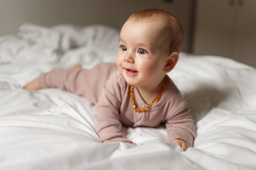 Cute baby girl lying on front on the bed at home.