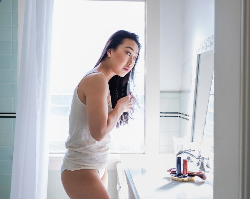 A woman dealing with hair loss during pregnancy combing her hair in a bathroom