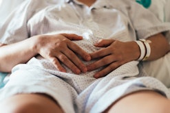 Woman with her hands on her belly after having a miscarriage