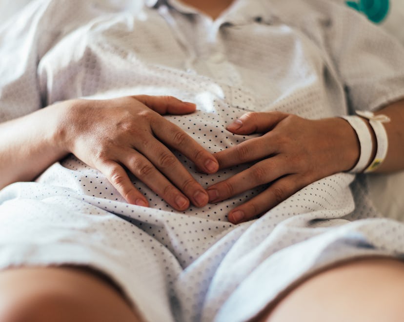 Woman with her hands on her belly after having a miscarriage