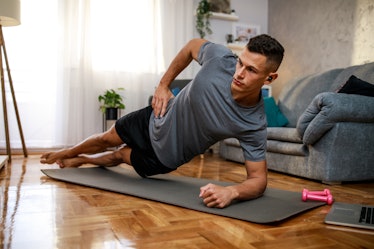 Young man doing a side plank to strengthen his core muscles at home.