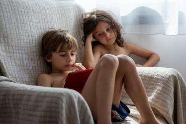 两个孩子使用数字平板电脑在客厅里。