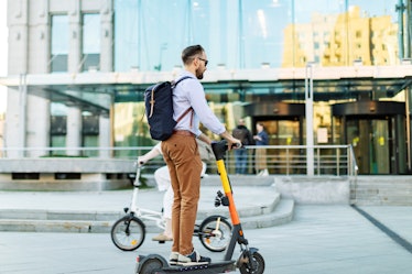 Young adult man using electro scooter at the city
